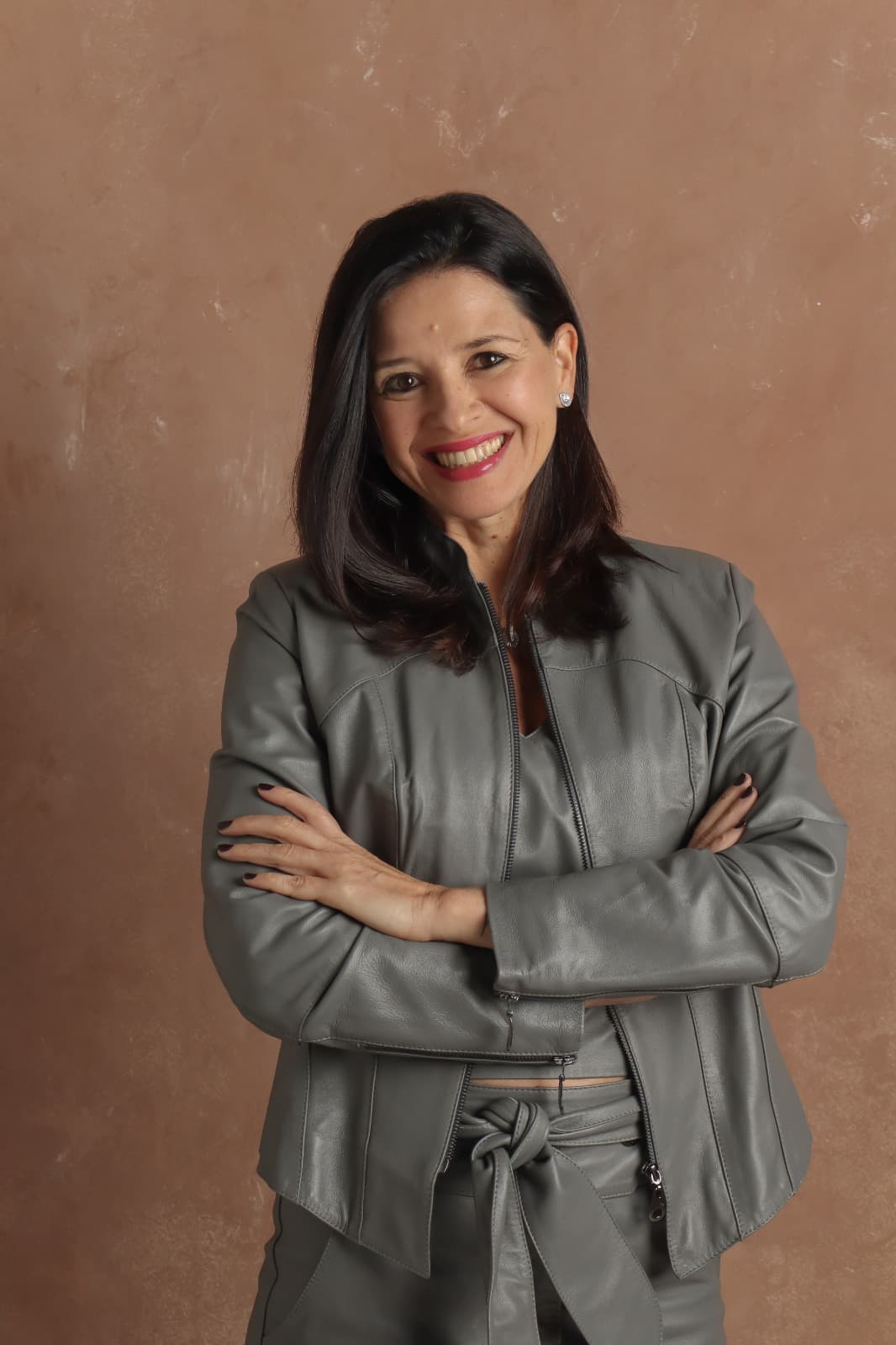 Fernanda Machado, criadora do NEXA, de braços cruzados diante de parede de tom terroso.